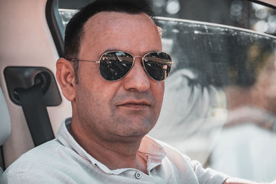 Portrait of man wearing sunglasses sitting in car