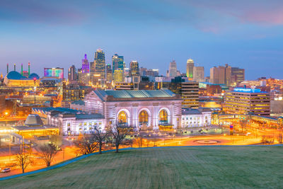 Illuminated buildings in city against sky at dusk