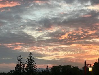 Low angle view of silhouette trees against dramatic sky