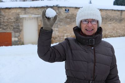 Portrait of smiling woman holding snow ball during winter