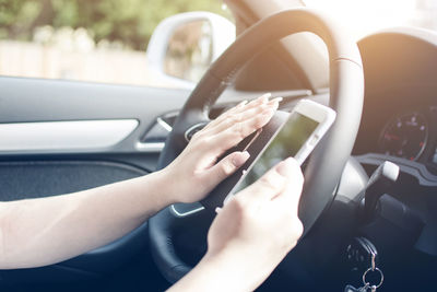 Cropped hands of woman using mobile phone in car