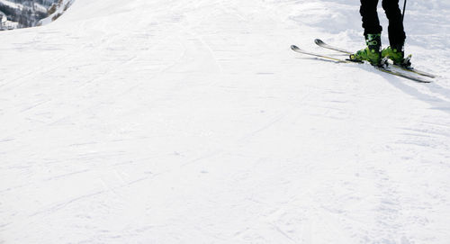 Low section of man walking on snow covered landscape