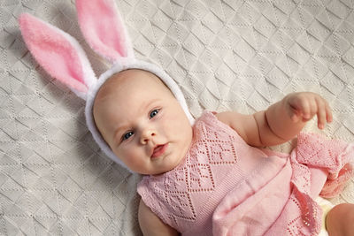 Funny little child is wearing bunny ears on cozy background. happy easter. baby girl in pink dress