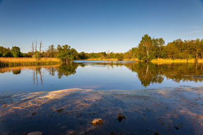 Scenic view of lake against clear blue sky