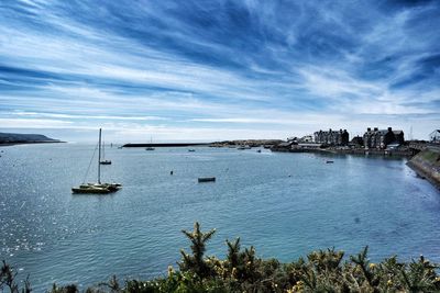 Boats in sea against cloudy sky