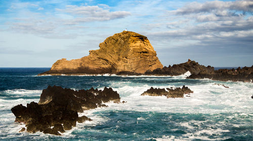 Rock formation by sea against sky