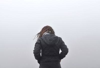 Rear view of woman standing against white wall