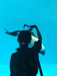 Woman photographing fish in aquarium