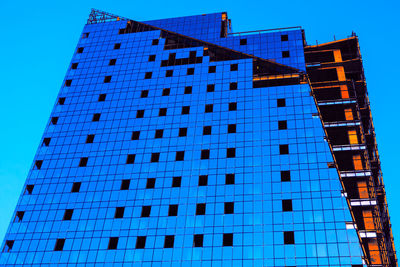 Low angle view of modern building against blue sky