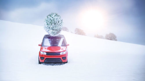 Red toy car on snow field against sky