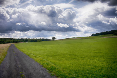 Road amidst field against sky