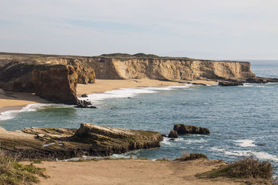 Rock formations by sea against sky