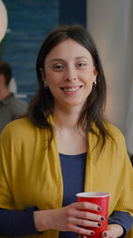 Portrait of a smiling young woman drinking drink