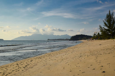 Waves of the azure andaman sea under the blue sky reaching the shores of cenang beach