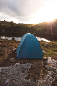 Tent near a lake against cloudy sky and sunset