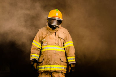 Firefighter in helmet standing against smoke