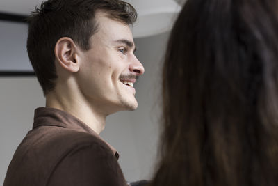 Low angle view of smiling young man with mustache at home