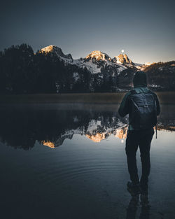 Rear view of man standing by lake against sky