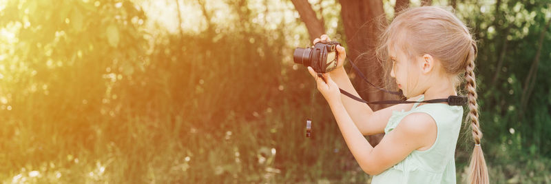 Young woman photographing plants on field