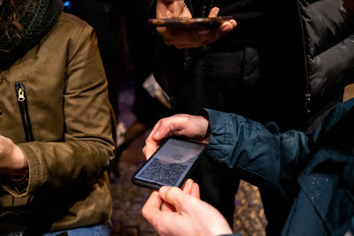 Midsection of man holding smart phone with bar code