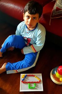 High angle portrait of boy sitting on floor at home