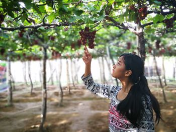 Young woman standing against tree