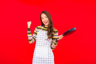 Portrait of a smiling young woman against red background