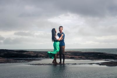 Full length of friends standing on beach against sky