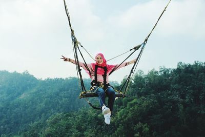 Person holding rope against trees in forest