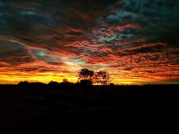 Scenic view of dramatic sky over silhouette landscape during sunset