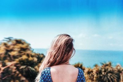 Woman looking at sea against clear blue sky