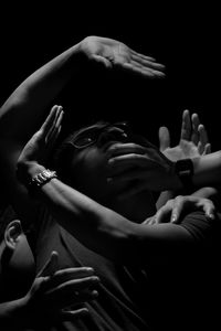 Cropped hands covering man face over black background