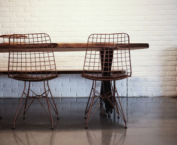 Empty chairs and table against wall