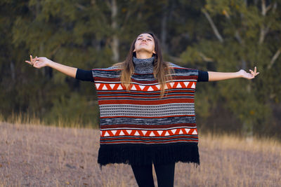 Young woman standing against trees