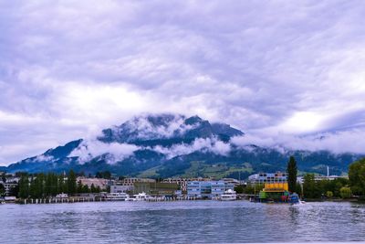 Scenic view of river by buildings against sky