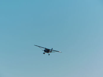 Low angle view of airplane against clear blue sky