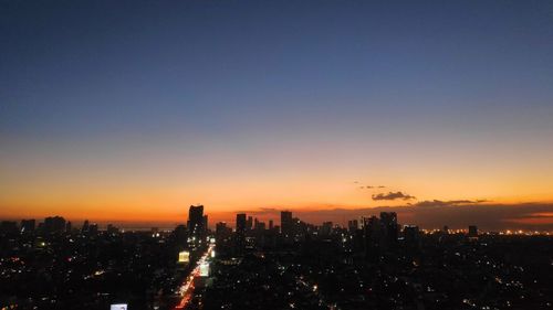 Silhouette buildings in city against sky during sunset