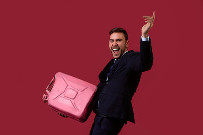 Man holding camera while standing against red background