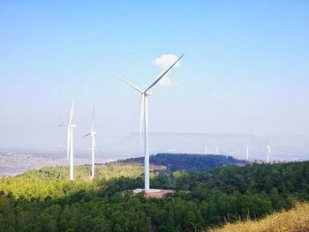 Wind turbines on field against sky