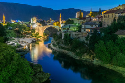 Bridge over river amidst buildings against sky