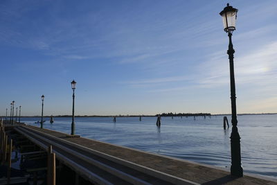 Street light by sea against sky