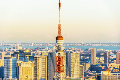 Communications tower in city against sky