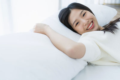 Portrait of smiling young woman relaxing on bed at home