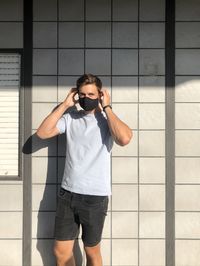 Young man photographing against wall