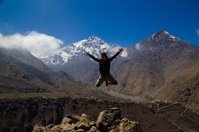 Playful man jumping against mountains during winter