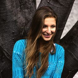 Close-up of woman smiling while standing against tree trunk