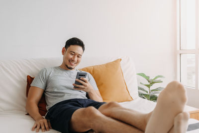 Young woman using laptop while sitting on sofa at home