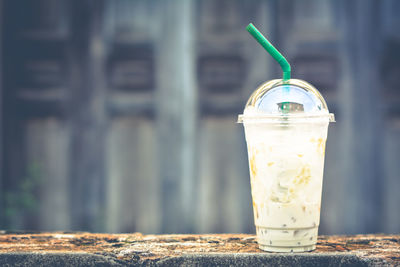 Close-up of fresh drink in disposable cup on retaining wall