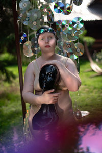 Portrait of young woman in a cap against the background of cd disks holds a mannequin in her hands