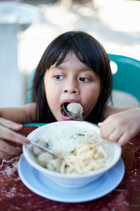 Cute girl eating food in bowl at home